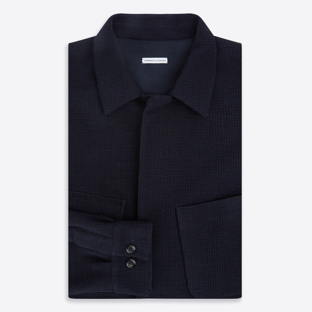 The Turnbull & Asser Navy Greenwich Knitted Overshirt, made from Italian wool with a collar, two front flap pockets, and a hidden button placket, is shown laid flat on a white background.