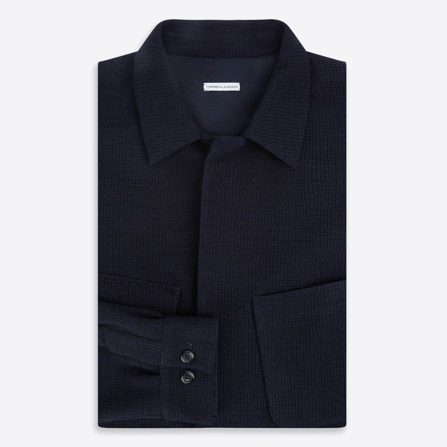 View 5 of product The Turnbull & Asser Navy Greenwich Knitted Overshirt, made from Italian wool with a collar, two front flap pockets, and a hidden button placket, is shown laid flat on a white background.