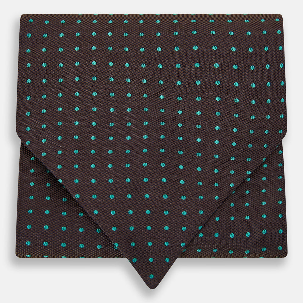 The Turnbull & Asser Blue and Dark Brown Micro Dot Silk Cravat features evenly spaced blue micro dots on dark brown silk, displayed neatly folded on a white background.