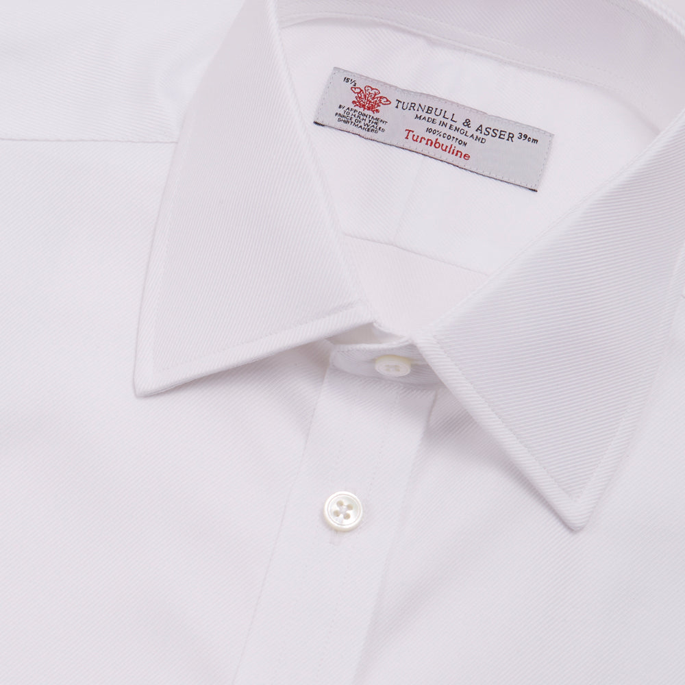 A neatly folded Turnbull & Asser White Oxford Shirt with T&A collar and double cuffs is displayed on a light blue background.