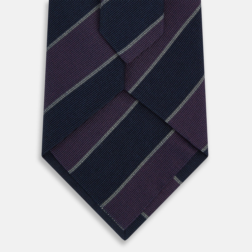 The Turnbull & Asser Purple And Navy Block Stripe Silk Blend Tie features dark navy and deep purple stripes with thin light gray lines, making it a refined formal accessory. Displayed on a white background.