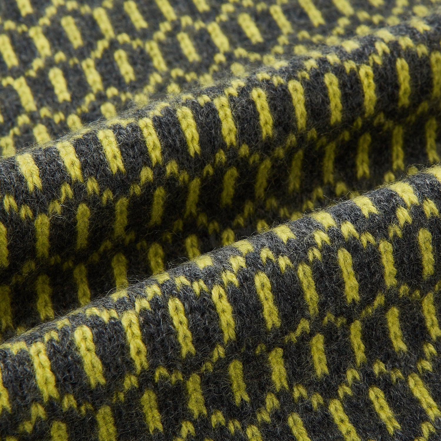 View 3 of product The Turnbull & Asser Graphite and Chartreuse Lemon Hexagon Cashmere Knitted Scarf features a geometric pattern in green and yellow tones, neatly folded to show both ends—an essential accessory with luxurious softness.