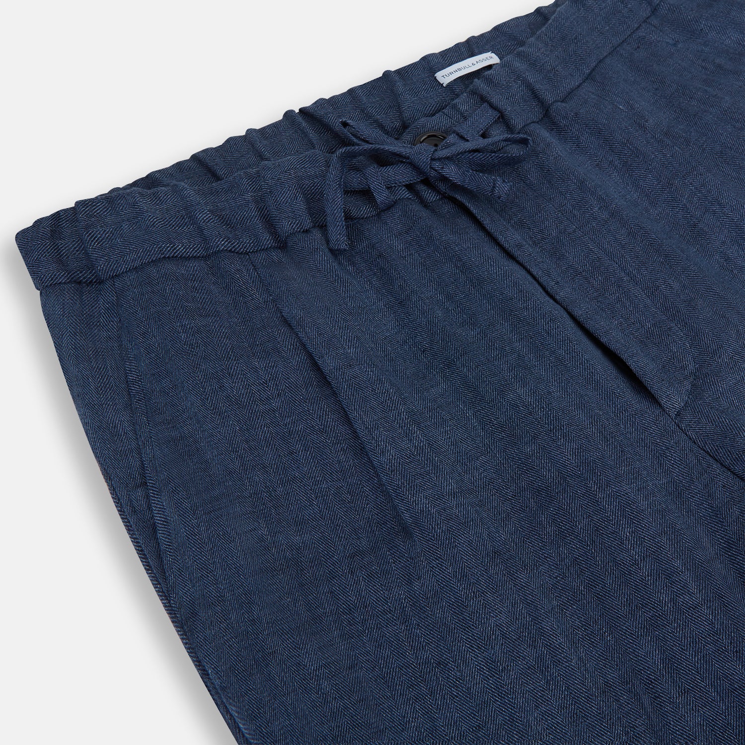 View 2 of product Turnbull & Asser Denim Blue Linen Herringbone Miles Trousers with a straight-leg fit, elasticated waist, and drawstring tie, shown against a plain white background.