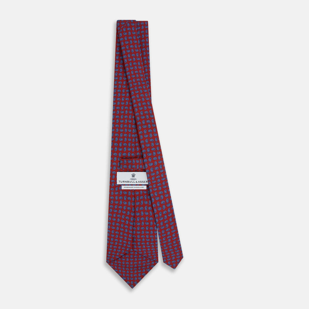 The Turnbull & Asser Red and Purple Miniature Paisley Silk Tie is neatly rolled with the pointed end facing forward.