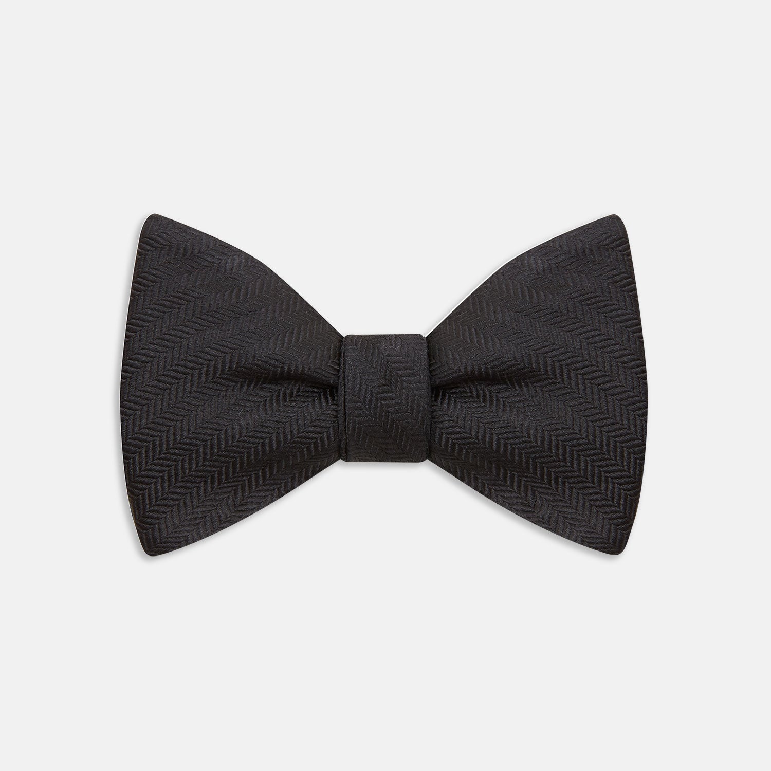View 1 of product The Turnbull & Asser Black Herringbone Silk Bow Tie, ideal for formal occasions, features a subtle herringbone pattern and is shown against a plain white background.
