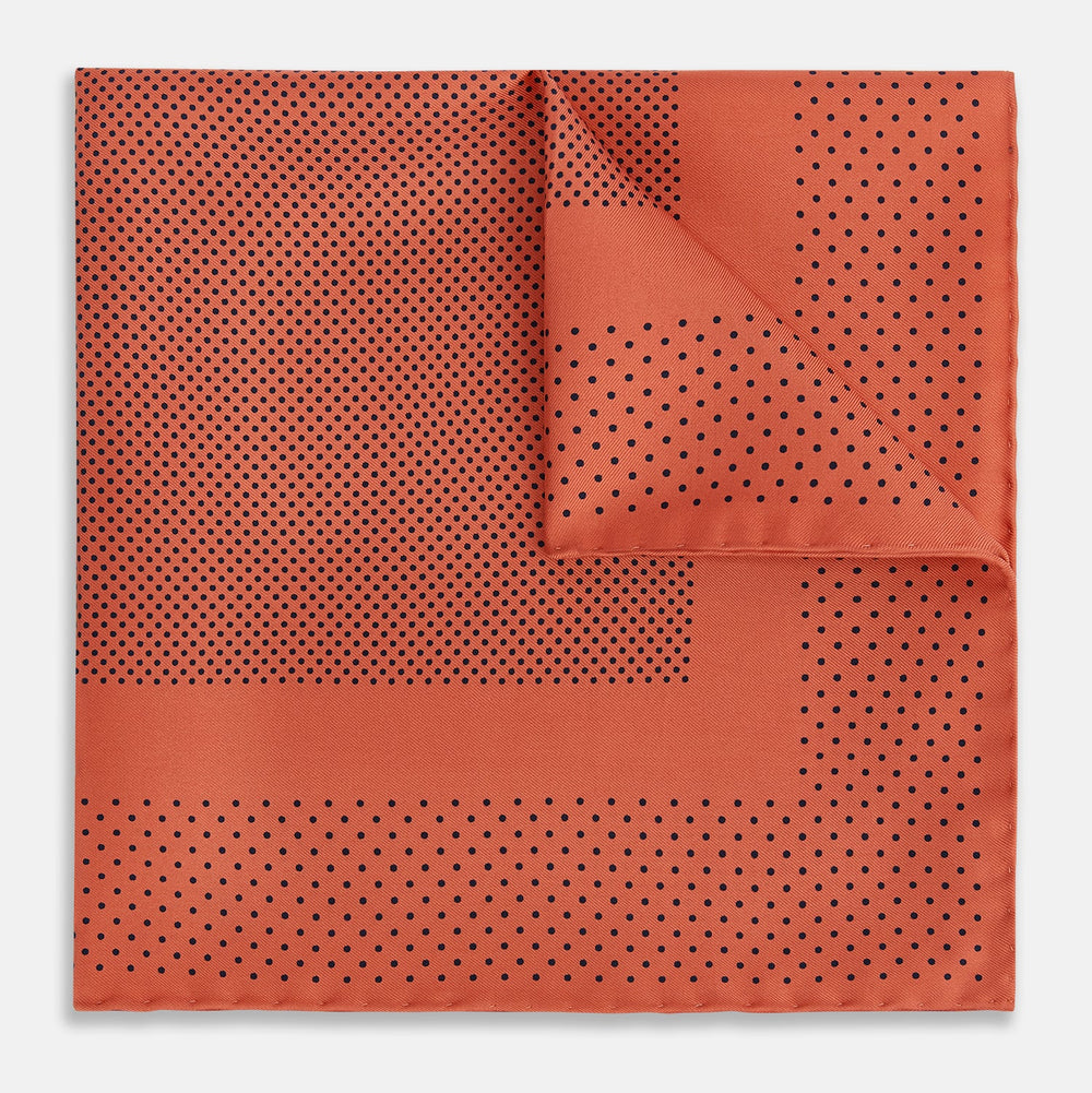 The Orange Dot Silk Pocket Square by Turnbull & Asser is handmade in England from silk, featuring small black polka dots and a solid orange border with a folded corner.
