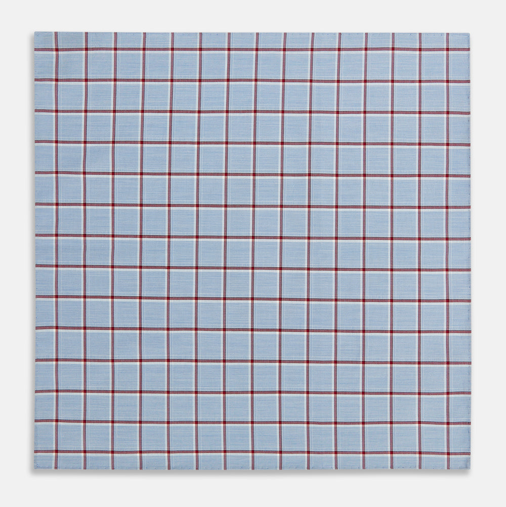 The Turnbull & Asser Blue and Burgundy Windowpane Check Hand-Rolled Handkerchief features a light blue fabric with white, red, and dark blue stripes forming a classic plaid grid.