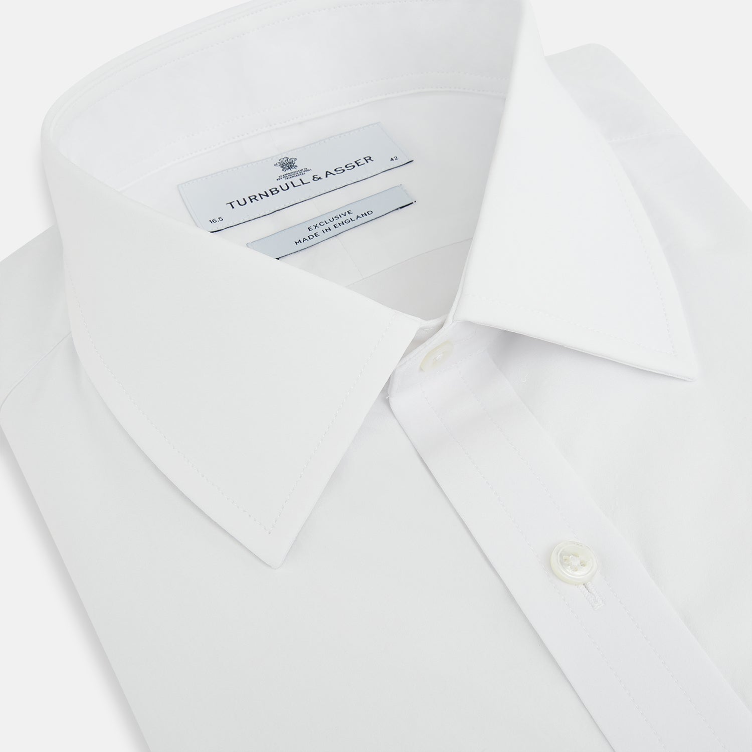 View 2 of product The White Mayfair Shirt by Turnbull & Asser features a classic collar, white buttons, and an inner branded label, all neatly crafted from premium sanforised cotton for lasting quality.