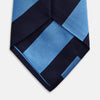 View 4 of product The BLOCK STRIPE NAVY RIVER TIE by Turnbull & Asser features bold navy and light blue diagonal stripes, rolled up neatly on a white background—a stylish essential for elevating any formal look.