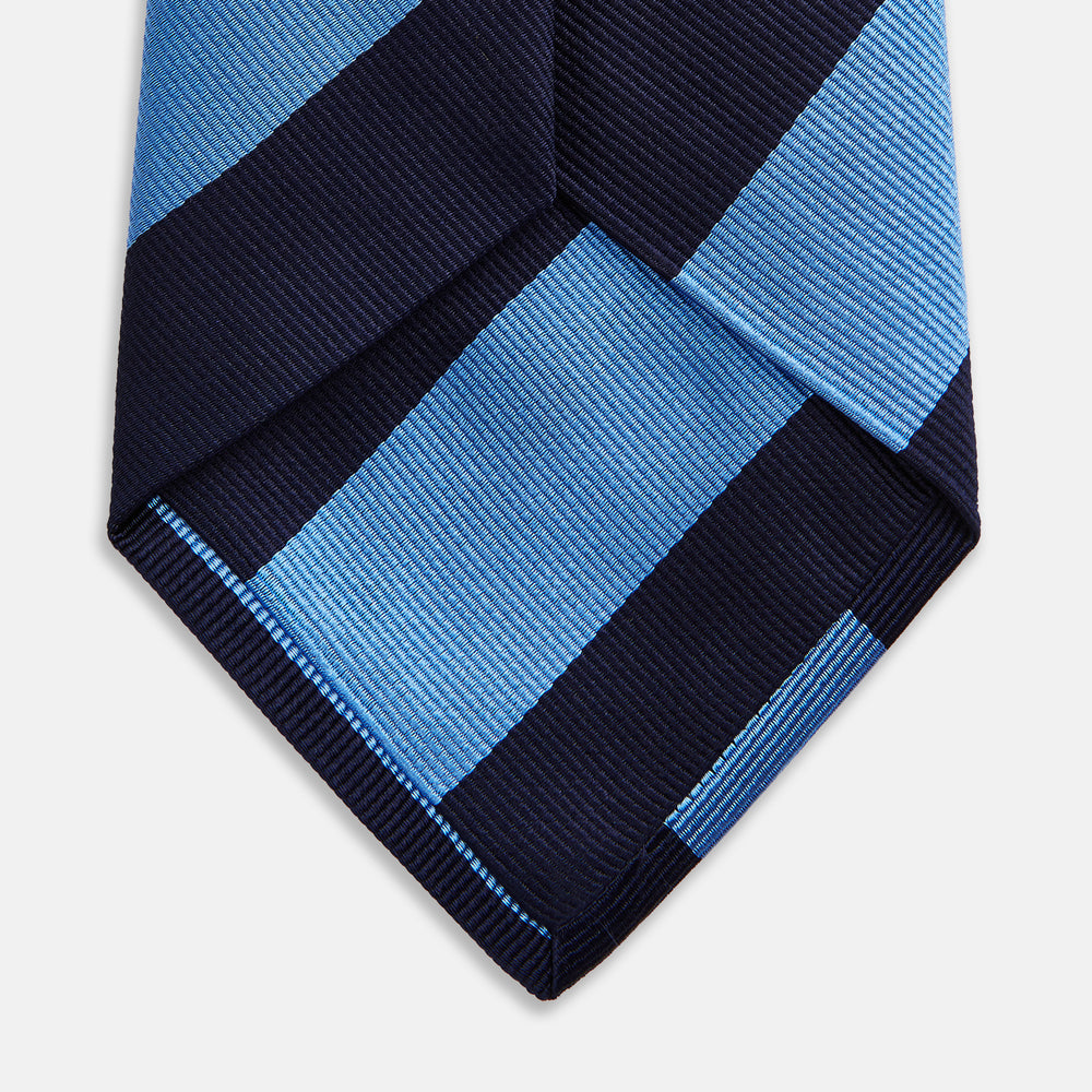 The BLOCK STRIPE NAVY RIVER TIE by Turnbull & Asser features bold navy and light blue diagonal stripes, rolled up neatly on a white background—a stylish essential for elevating any formal look.