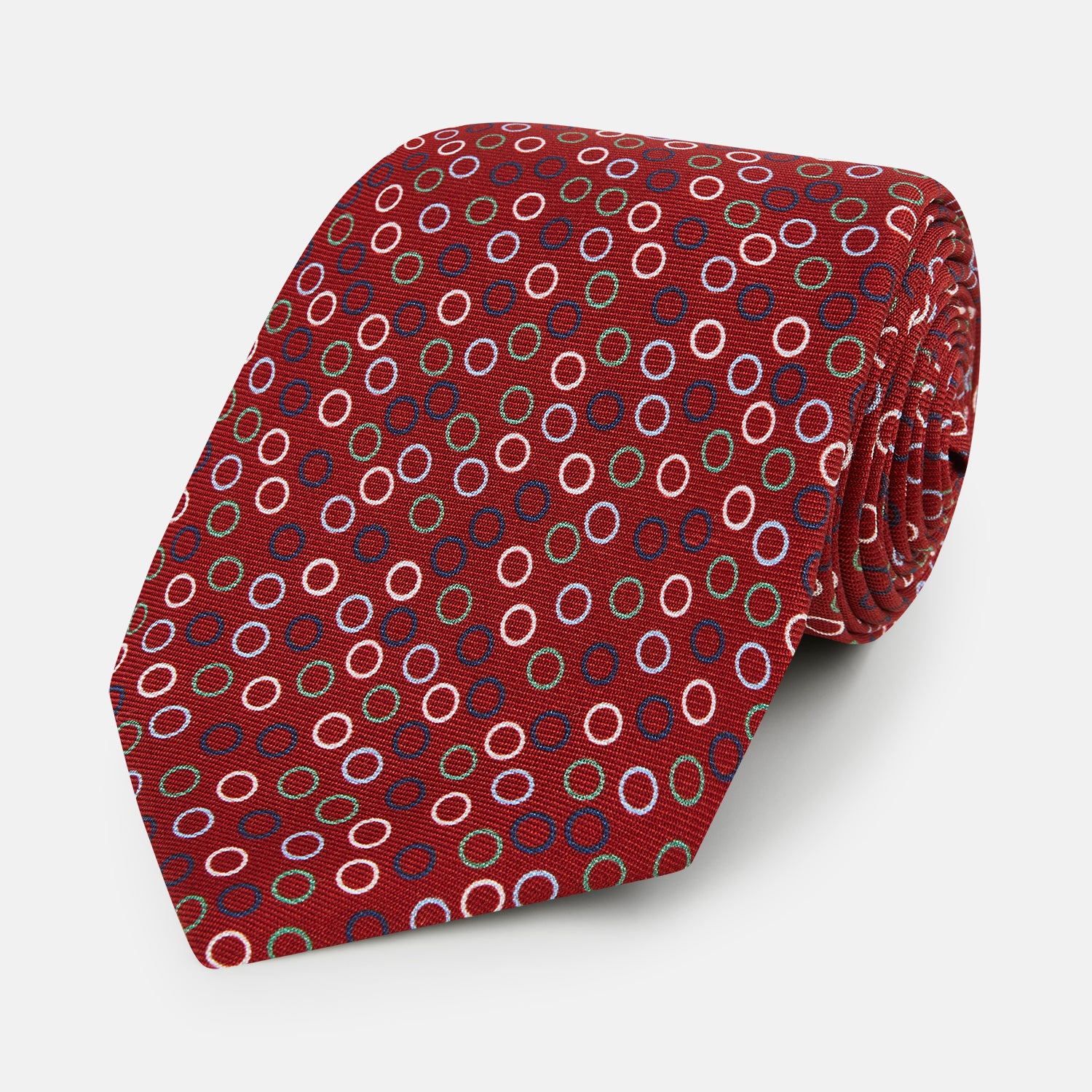 View 1 of product The Turnbull & Asser Pink and Navy Circle Red Silk Tie features small multicolored rings on red fine English silk. Rolled and displayed on a plain white background, this elegant accessory combines classic style with vibrant accents.