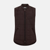 View 1 of product The Turnbull & Asser Burgundy Quilted Gilet is a sleeveless, lightweight layer featuring a front zipper, slanted chest pocket, adjustable side tabs, and two zippered side pockets, shown on a plain white background.