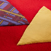 View 6 of product The Turnbull & Asser Red Applique Hand Stitched Lambswool Blanket features black-stitched edges and handsewn tie silk patches, including a yellow triangle and plaid triangle arranged to form a stylized fish.