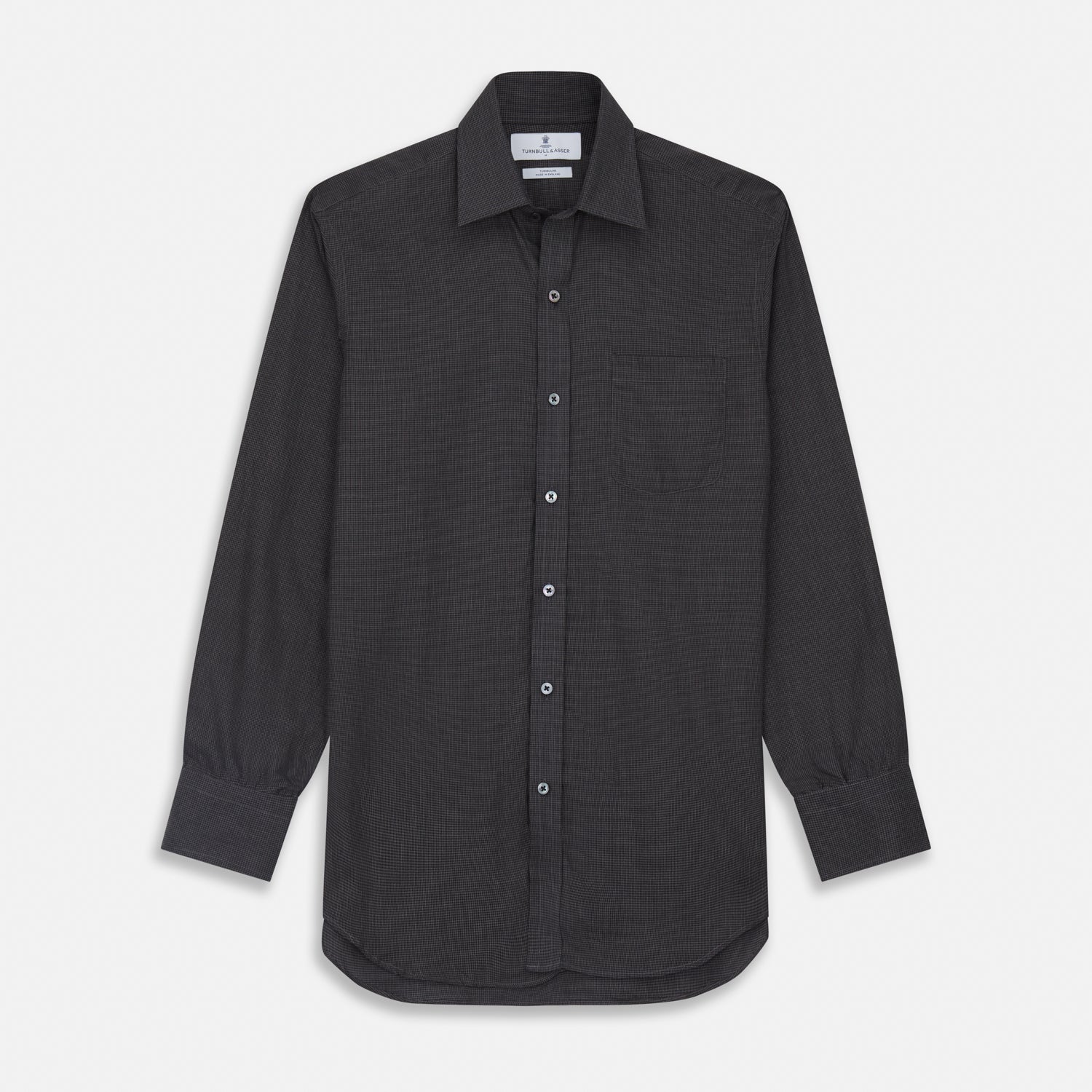 View 2 of product A man with short hair wears the Turnbull & Asser Black Check Weekend Fit Flannel Shirt with Derby Collar and 1-Button Cuffs, paired with light pants, against a plain background—ideal for a smart-casual weekend look.