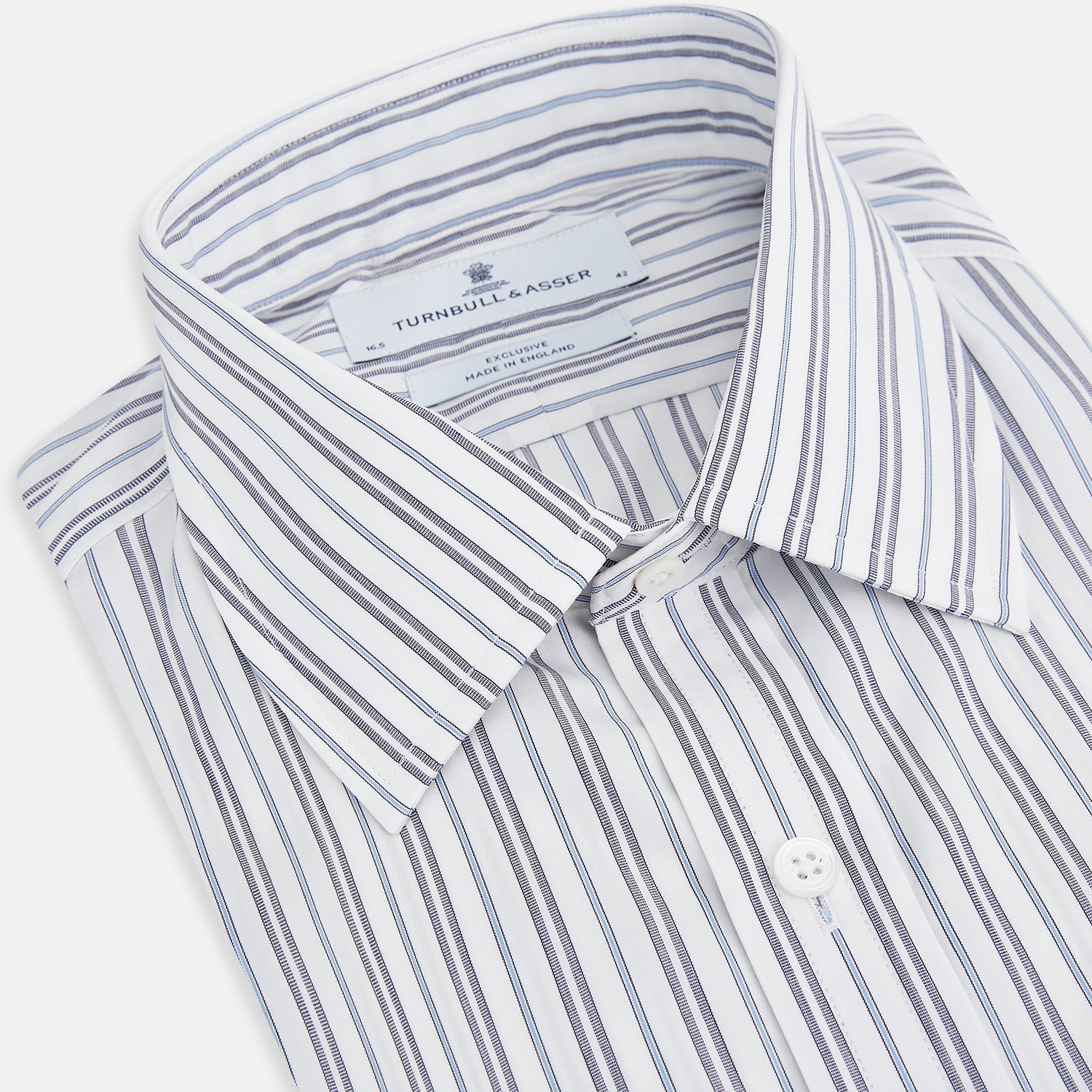 View 2 of product The Turnbull & Asser Navy Multi Stripe Mayfair Shirt features a T&A collar and premium Italian cotton, with vertical blue and white stripes. It is shown neatly laid flat on a white background.