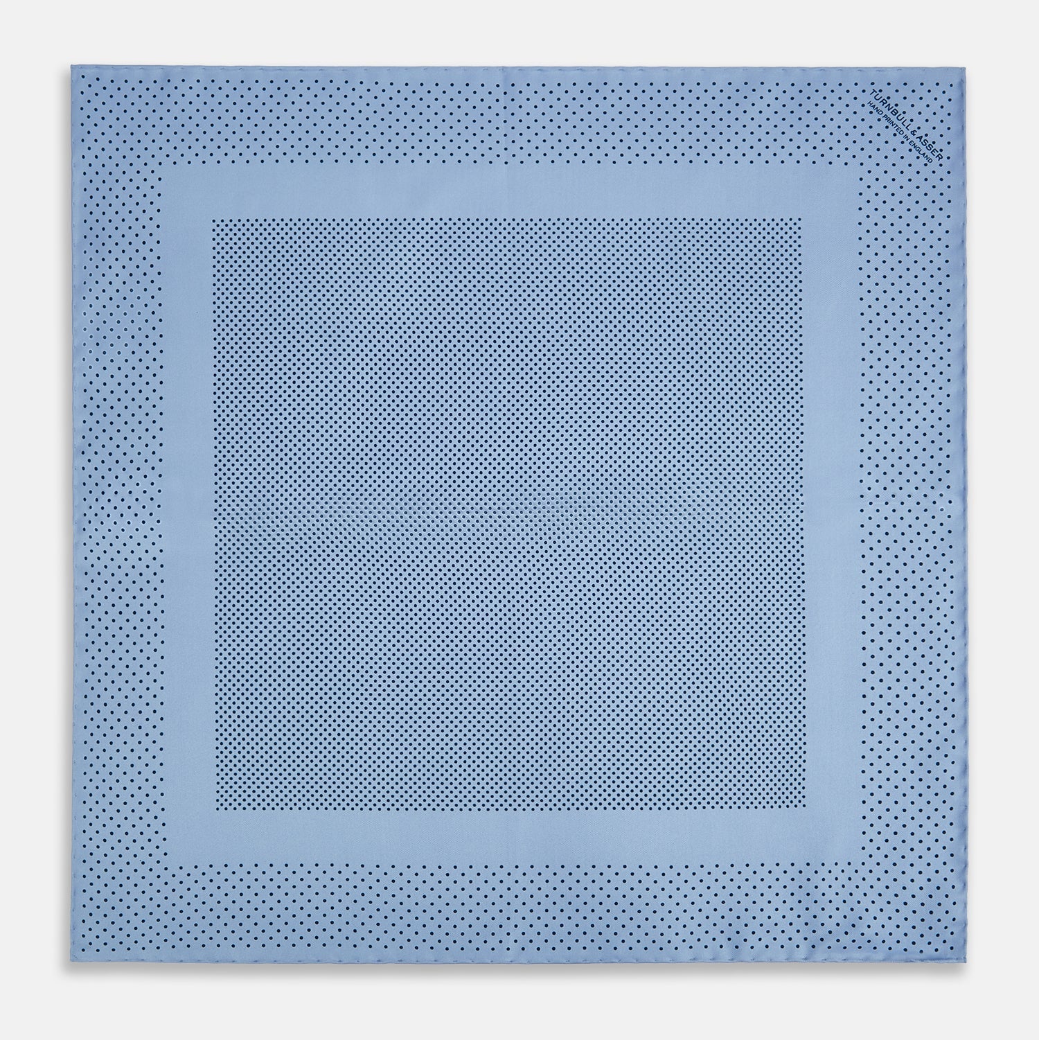 View 4 of product The Turnbull & Asser Pale Blue Dot Silk Pocket Square features pure silk in pale blue with a border and scattered small navy polka dots, neatly folded with one corner turned down.