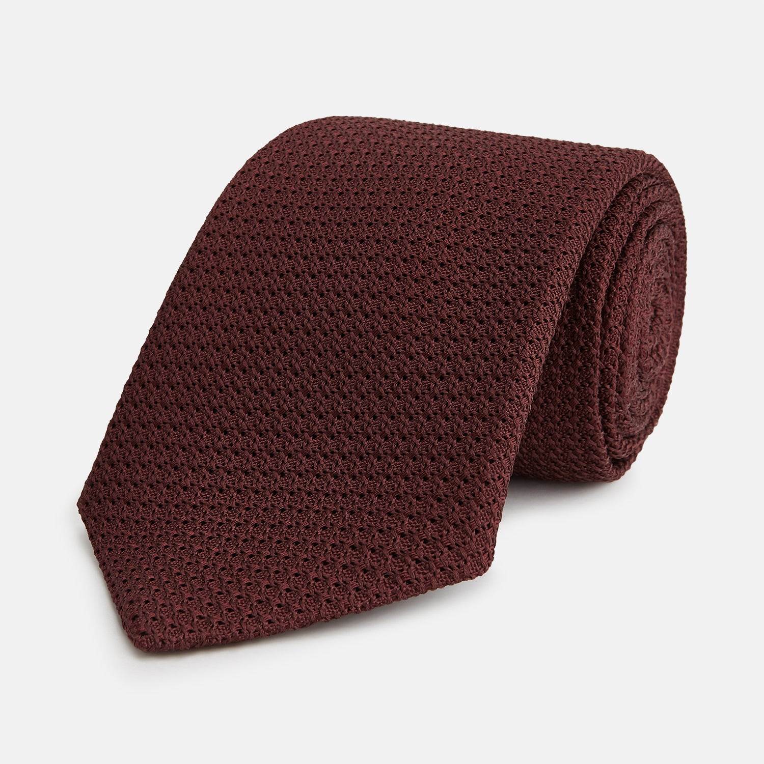 View 1 of product The Turnbull & Asser Ruby Red Knitted Tie, shown rolled-up against a white background, is a textured silk accessory that adds versatile sophistication to any gentleman's wardrobe.