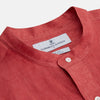 View 2 of product The Turnbull & Asser Plain Red Linen Weekend Fit Shirt with Stand Collar features long sleeves, a button-up front, and two buttoned-flap chest pockets. It is shown neatly laid flat on a plain light background.
