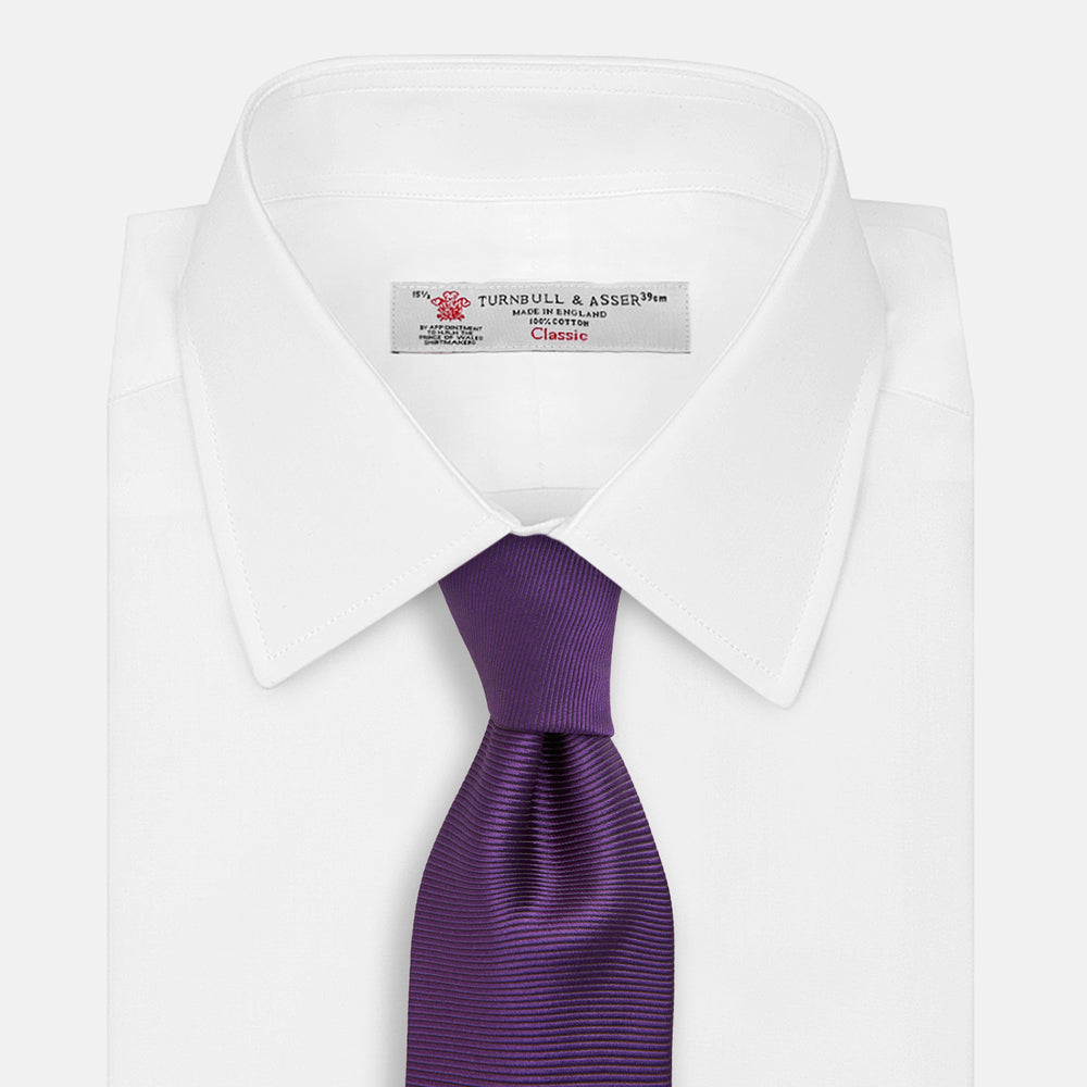 The HORIZONTAL TWILL PLUM TIE by Turnbull & Asser features a solid purple hue and smooth, subtly textured fabric—a versatile accessory to elevate any wardrobe, shown elegantly against a white background.