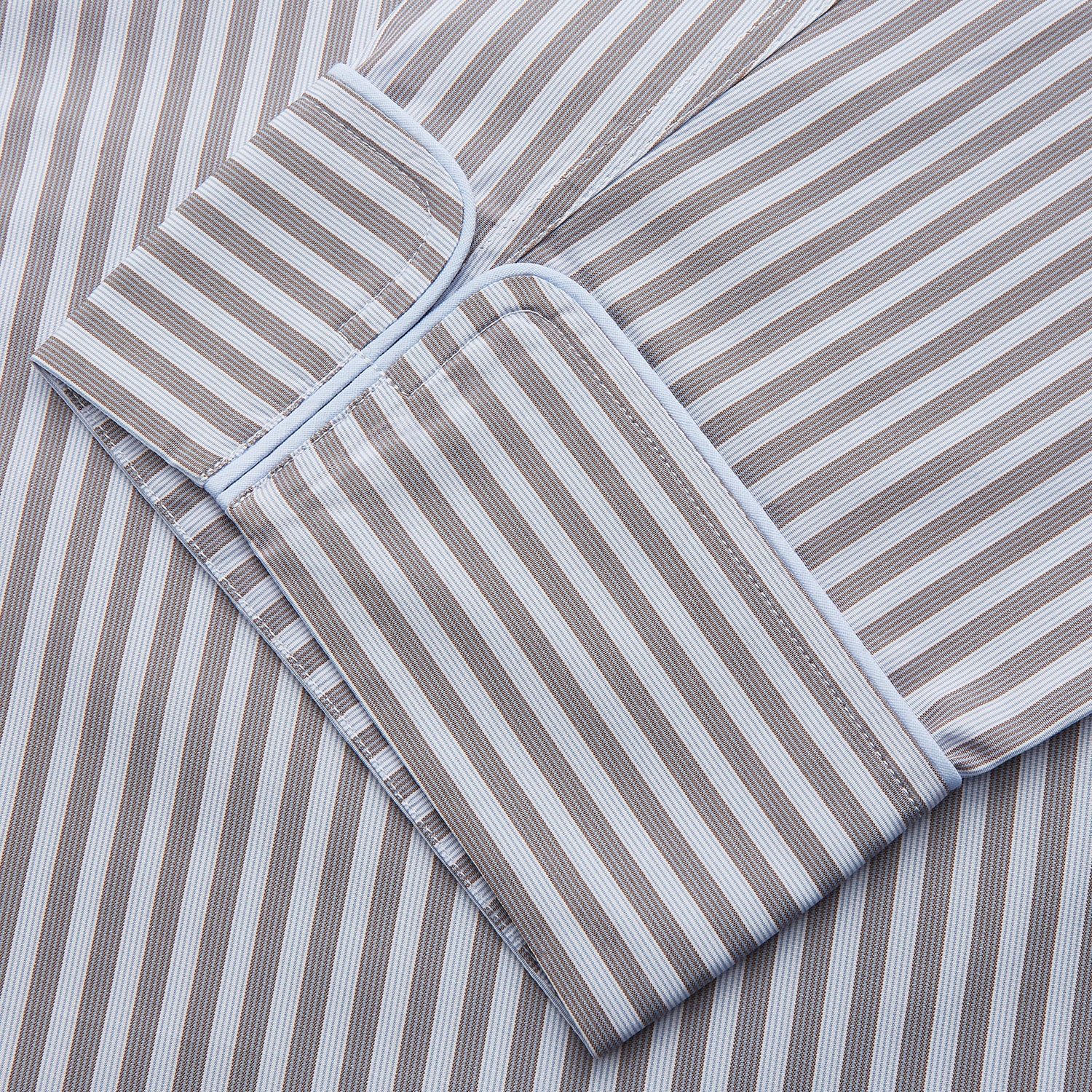 View 2 of product The Turnbull & Asser Pale Blue Multi Stripe Cotton Quin Pyjamas, featuring a long-sleeve button-up top and matching adjustable tie-waist pants, are neatly arranged on a white background.