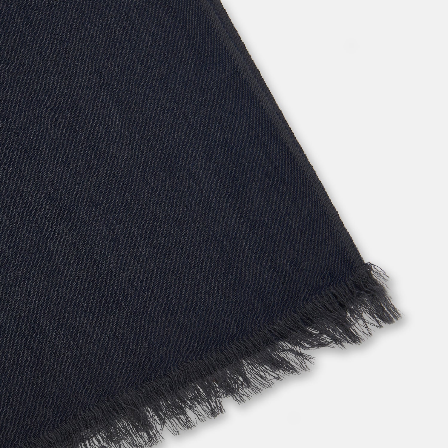 View 2 of product The Charcoal and Navy Cashmere Scarf by Turnbull & Asser features a color block design in dark hues, raw fringed edges, and a soft, smooth texture, elegantly displayed against a white background.