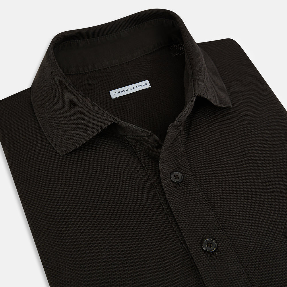 A brown cotton jersey polo shirt by Turnbull & Asser with short sleeves, a collar, three buttons, and a buttoned chest pocket, laid flat on a white background.