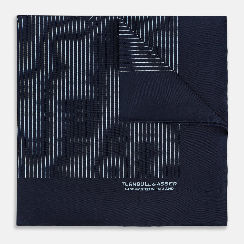 The Turnbull & Asser Navy and Light Blue Stripe Silk Pocket Square features hand-rolled edges and "Turnbull & Asser Hand Printed in England" in white text.
