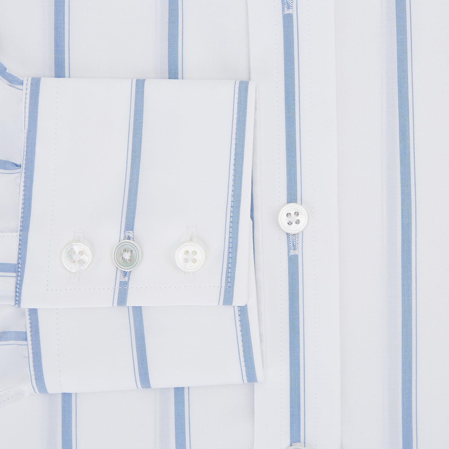 View 4 of product The Colony Blue Track Stripe Mayfair Shirt by Turnbull & Asser is a long-sleeve, button-up Italian cotton shirt with a white base and blue stripes, pointed collar, and buttoned cuffs, shown laid flat on a white background.