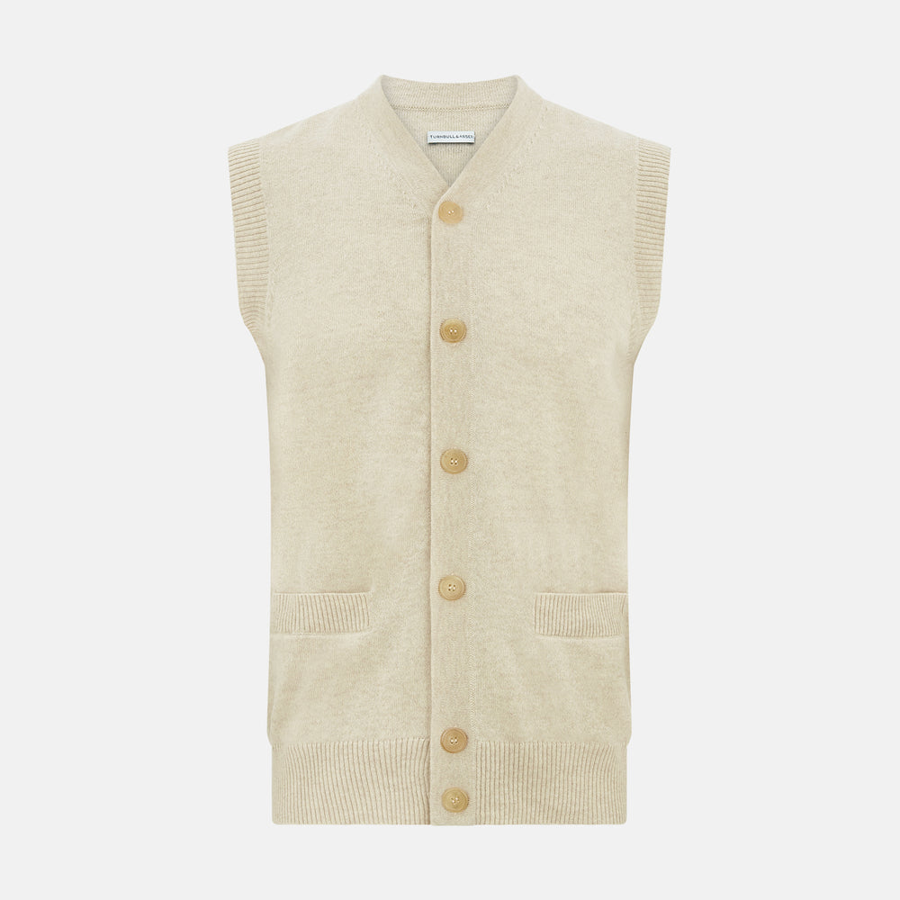 Turnbull & Asser’s Ivory Cashmere Sleeveless Cardigan features a button-down front, two small pockets, and ribbed trim at the hem, armholes, and collar—ideal for elegant looks. Shown on a white background.