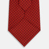 View 3 of product The Turnbull & Asser Red Lattice-Patterned Silk Tie features a subtle black lattice design with small circular motifs, shown rolled up on a plain white background.