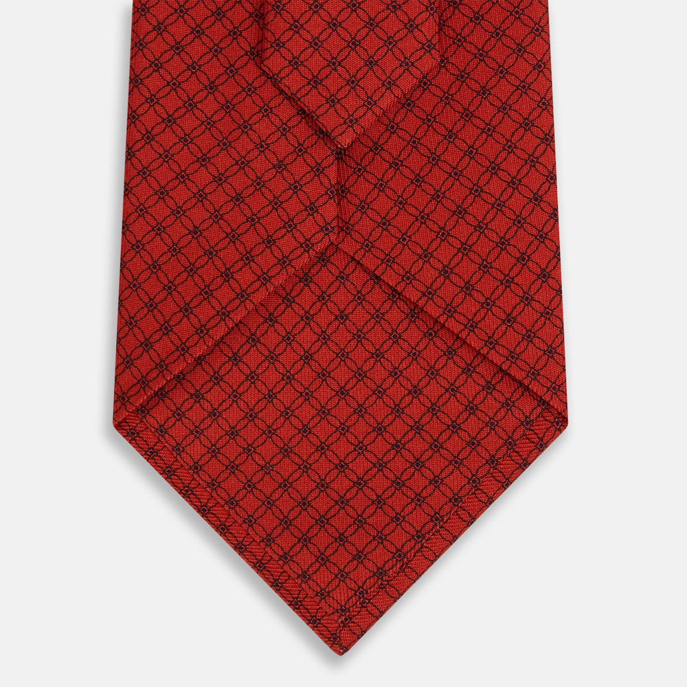 The Turnbull & Asser Red Lattice-Patterned Silk Tie features a subtle black lattice design with small circular motifs, shown rolled up on a plain white background.