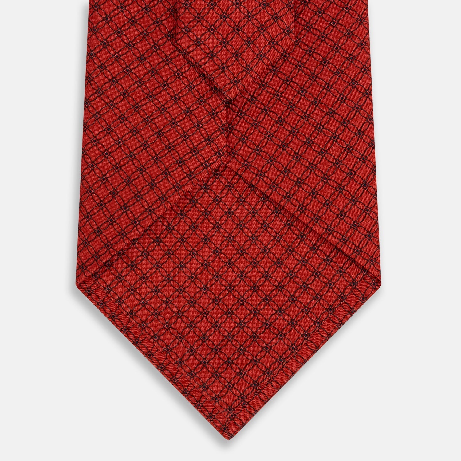 View 3 of product The Turnbull & Asser Red Lattice-Patterned Silk Tie features a subtle black lattice design with small circular motifs, shown rolled up on a plain white background.
