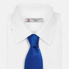 View 2 of product The Turnbull & Asser Plain Herringbone Cruise Tie in bright blue, shown rolled up on a white background, features a subtle chevron pattern—an essential finishing touch for your smart look.