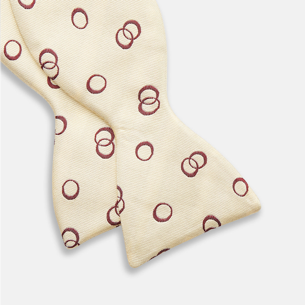 The Yellow Geometric Rings Silk Bow Tie by Turnbull & Asser features interlocking rings in a bold geometric pattern, crafted from silk.