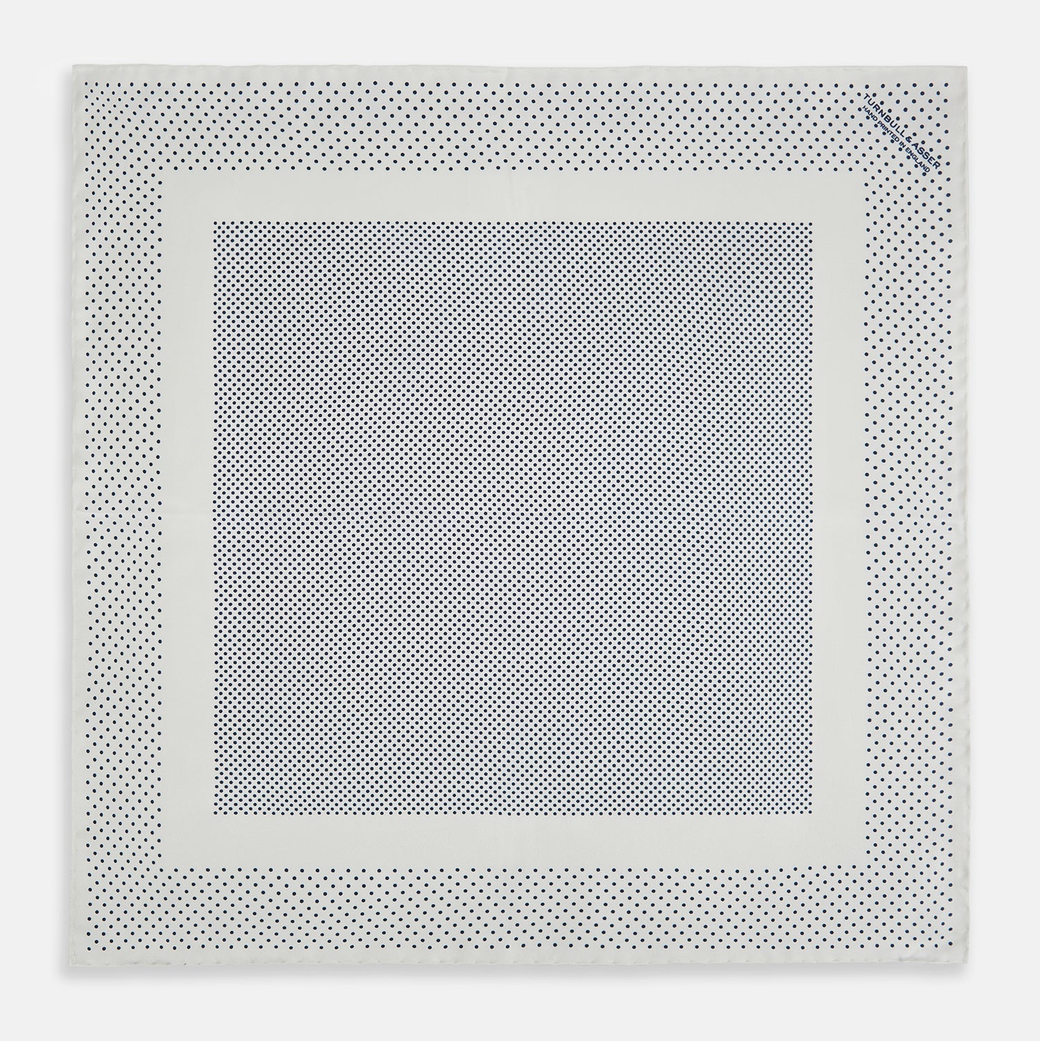 View 4 of product The Turnbull & Asser Cream Dot Silk Pocket Square features a neatly folded pure silk design with a border and center pattern of small navy blue polka dots, displayed on a plain white background.