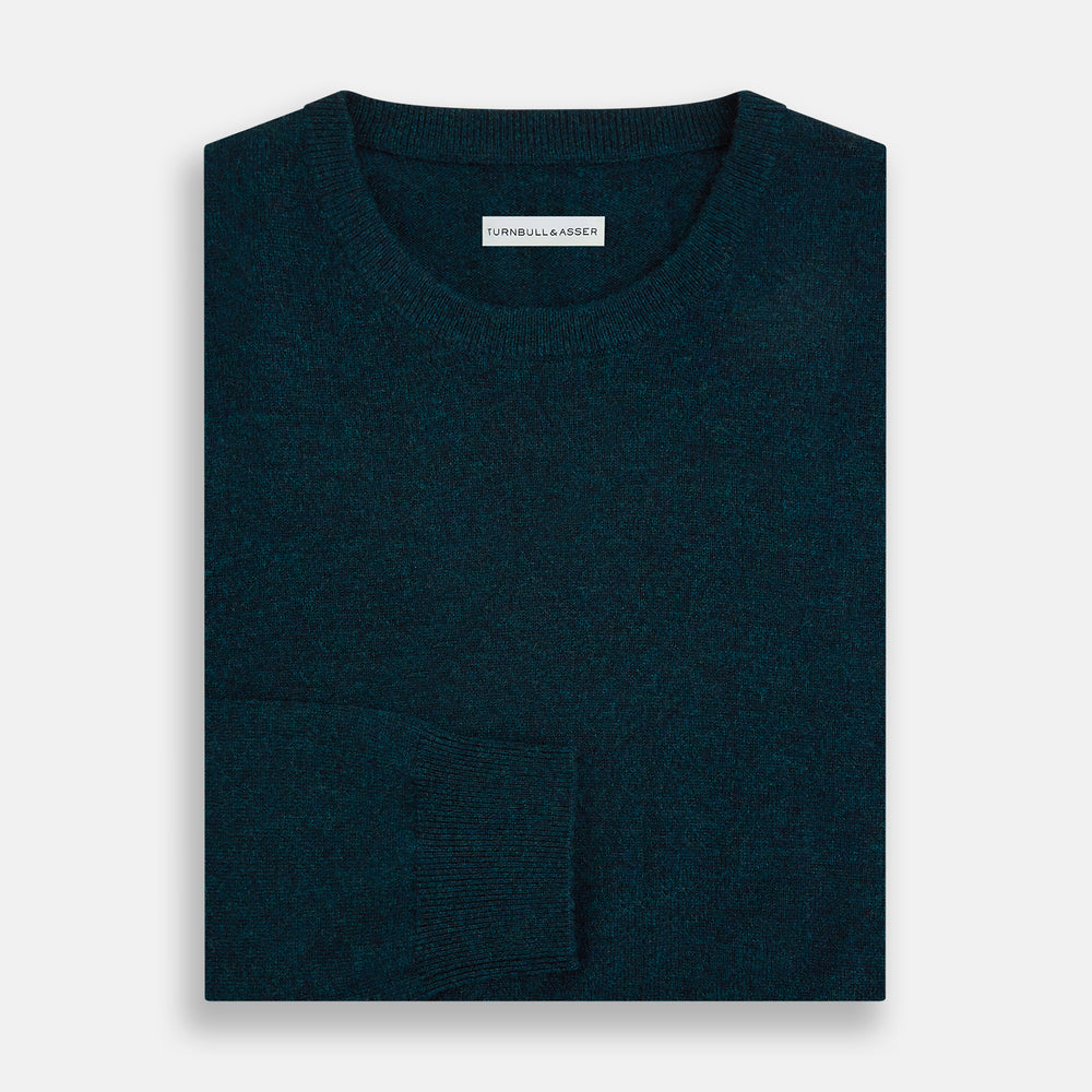 The Turnbull & Asser Dark Green Melange Cashmere Round Neck Jumper features long sleeves with ribbed cuffs and a ribbed hem, shown against a plain white background.