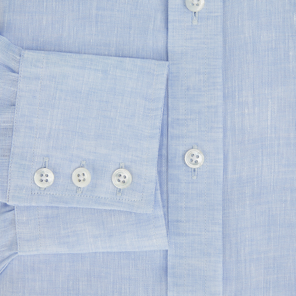 The Turnbull & Asser Pale Blue Linen Mayfair Shirt features a collar, front pocket, and white buttons. This long-sleeve shirt is displayed on a white background.