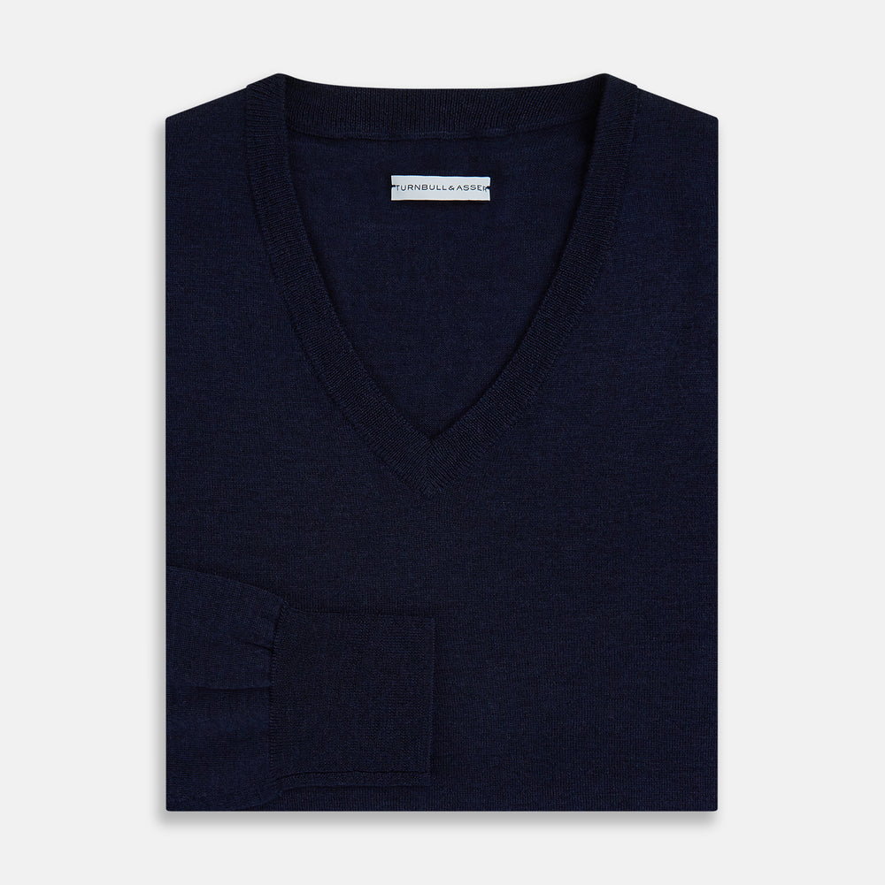 The Turnbull & Asser Navy Fine Merino V-Neck Jumper is displayed against a white background, featuring ribbed cuffs and hem for timeless style in a classic, plain long-sleeve design.