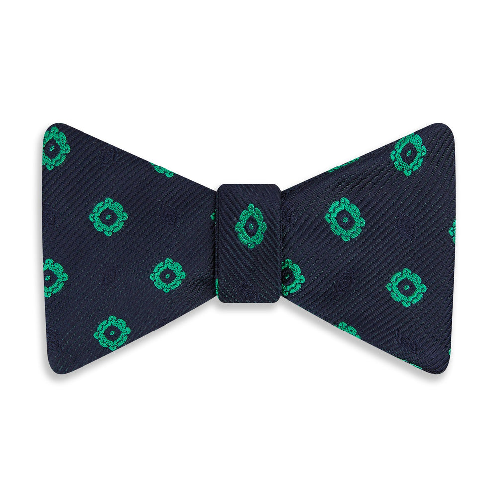 The Navy and Green Motif Silk Bow Tie by Turnbull & Asser features geometric floral patterns, ideal for formalwear, and is shown on a white background.