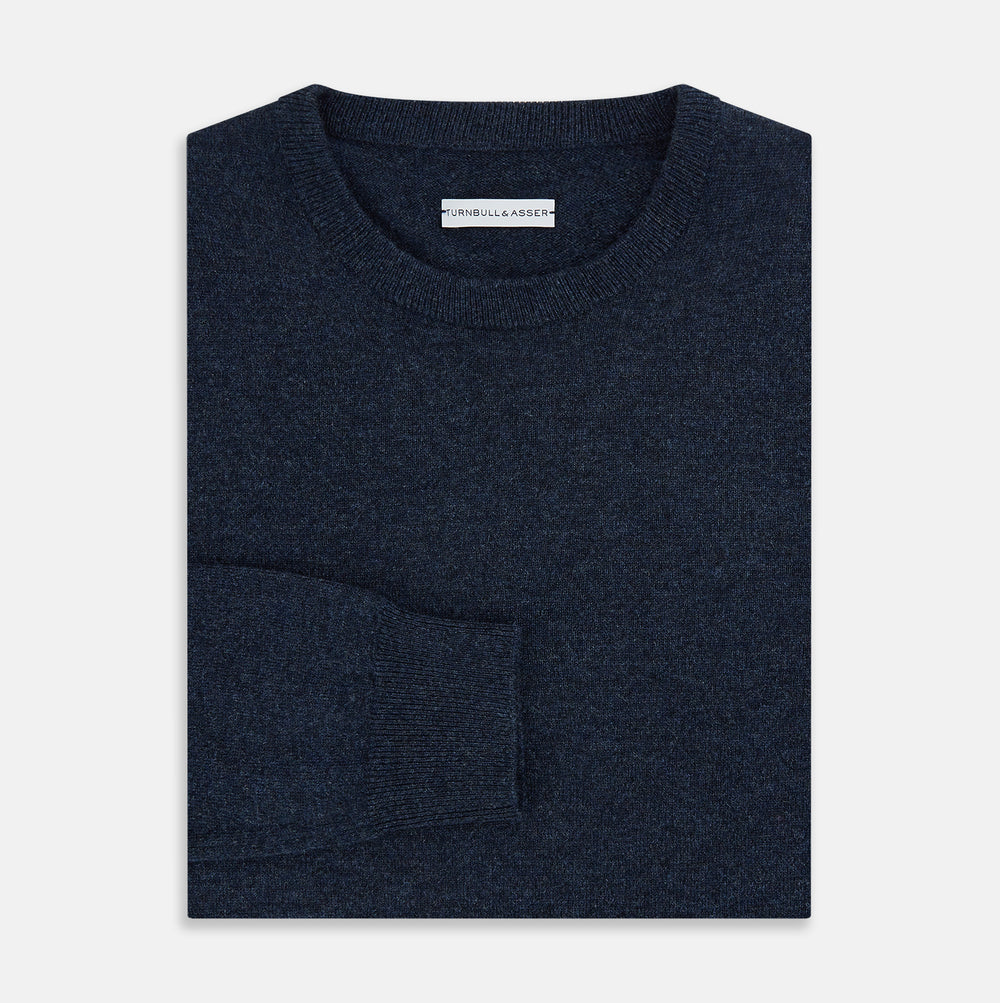 The Turnbull & Asser Midnight Blue Cashmere Round Neck Jumper, featuring long sleeves and ribbed trims, is shown against a light grey background.