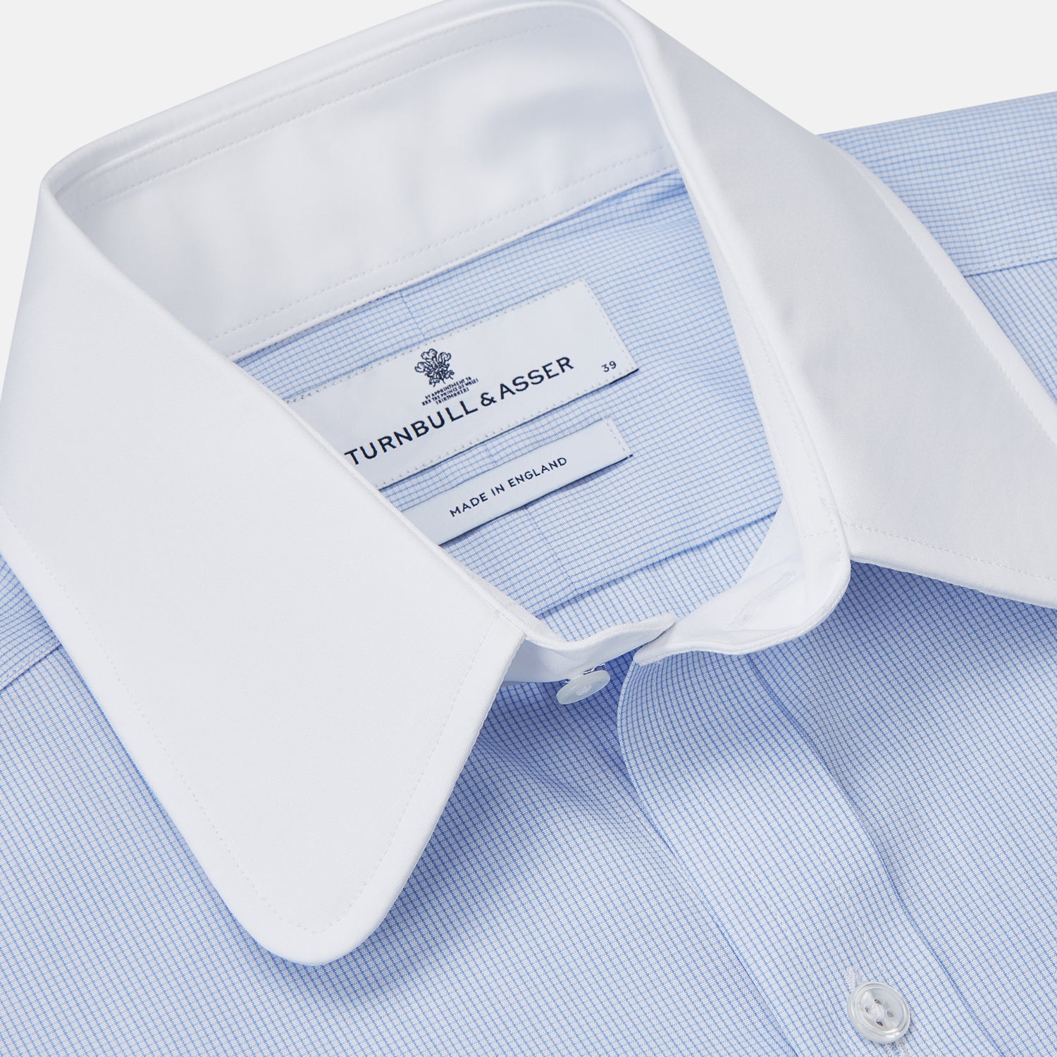 View 4 of product The Turnbull & Asser Micro Blue Check with White Collar and Cuff Shirt, a light blue long-sleeve style, features contrasting white collar and cuffs, buttoned down the front and laid flat on a white background.