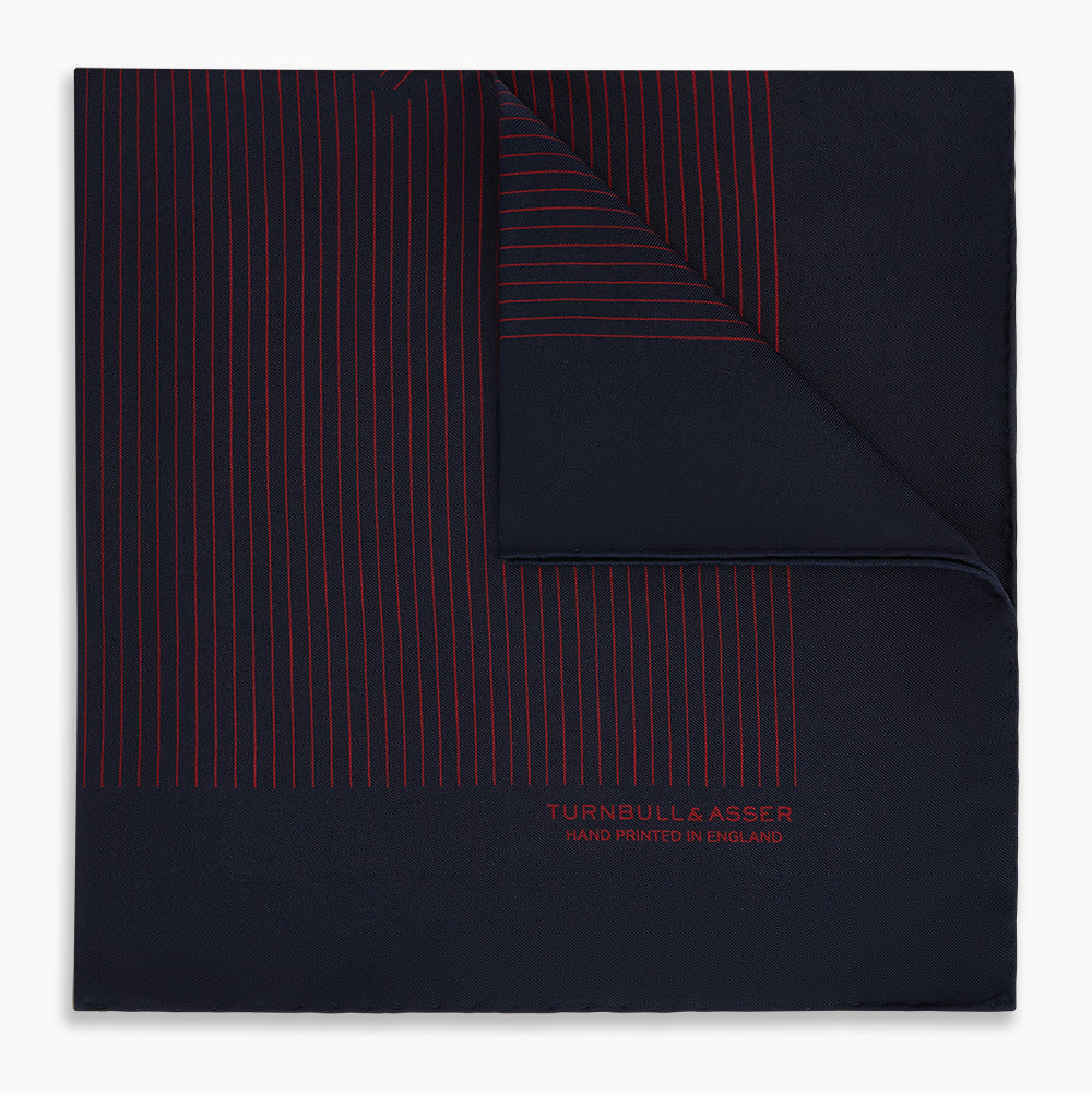 The Turnbull & Asser Navy and Burgundy Stripe Silk Pocket Square features diagonal stripes in one corner, hand-rolled edges, and "TURNBULL & ASSER HAND PRINTED IN ENGLAND" printed in red on luxurious silk.