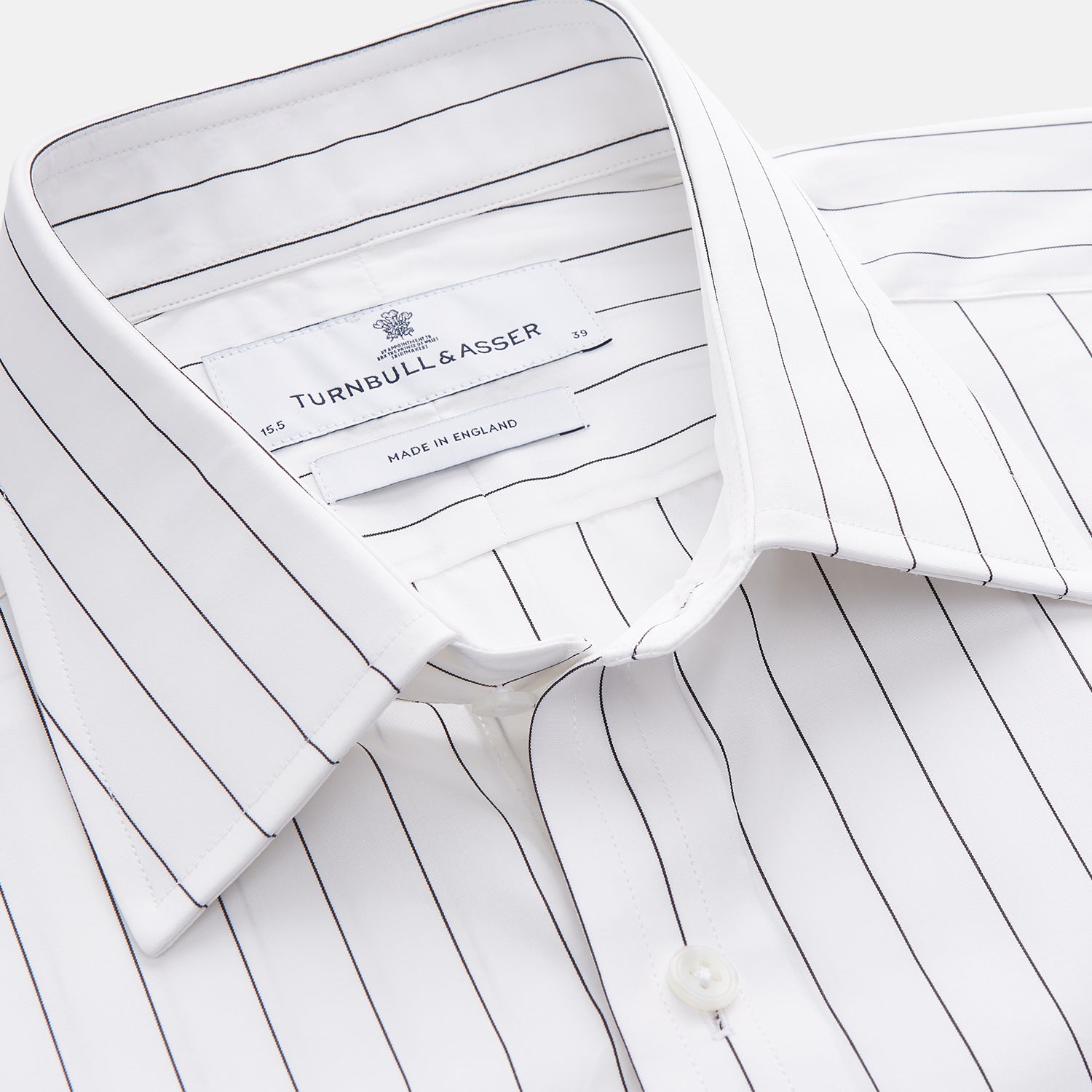 View 4 of product The Turnbull & Asser Black Fine Stripe Cotton Regular Fit Mayfair Shirt features a T&A collar, buttoned cuffs, and black fine stripes, displayed flat on a white background.