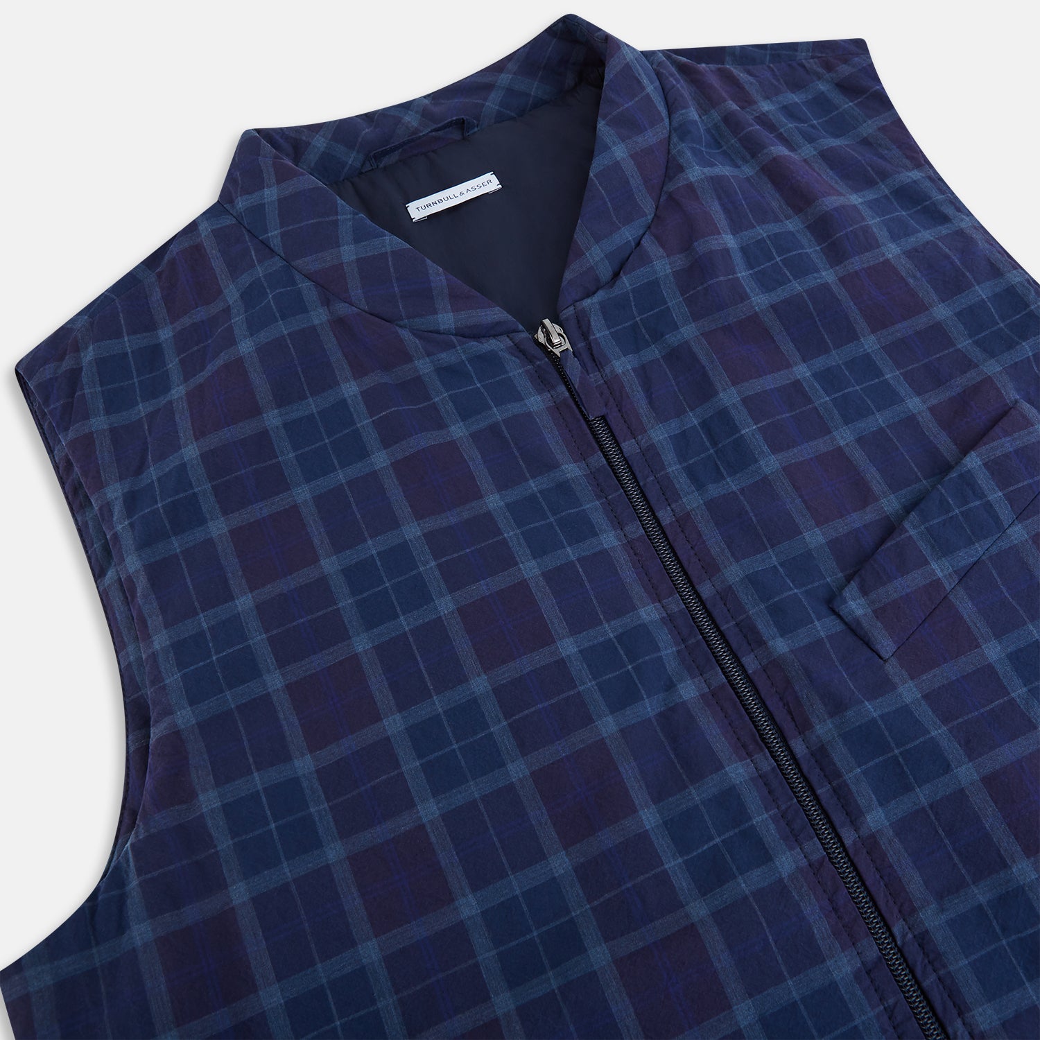 View 2 of product The Turnbull & Asser Navy and Purple Plaid Check Padded Gilet is sleeveless, has a front zipper, two zippered side pockets, a small chest pocket, and is shown on a plain white background.