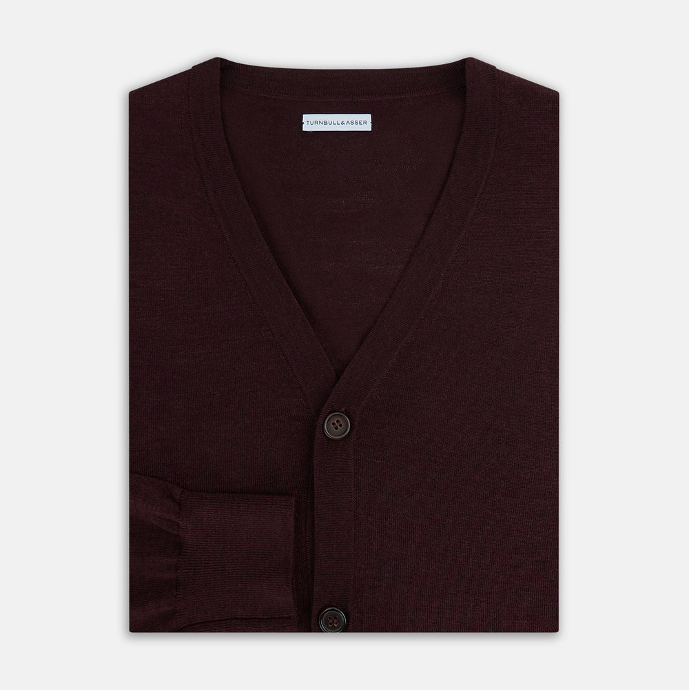 The Turnbull & Asser Burgundy Fine Merino V-Neck Cardigan features long sleeves and a button-down front, highlighting elegant handcrafted knitwear against a plain white background.