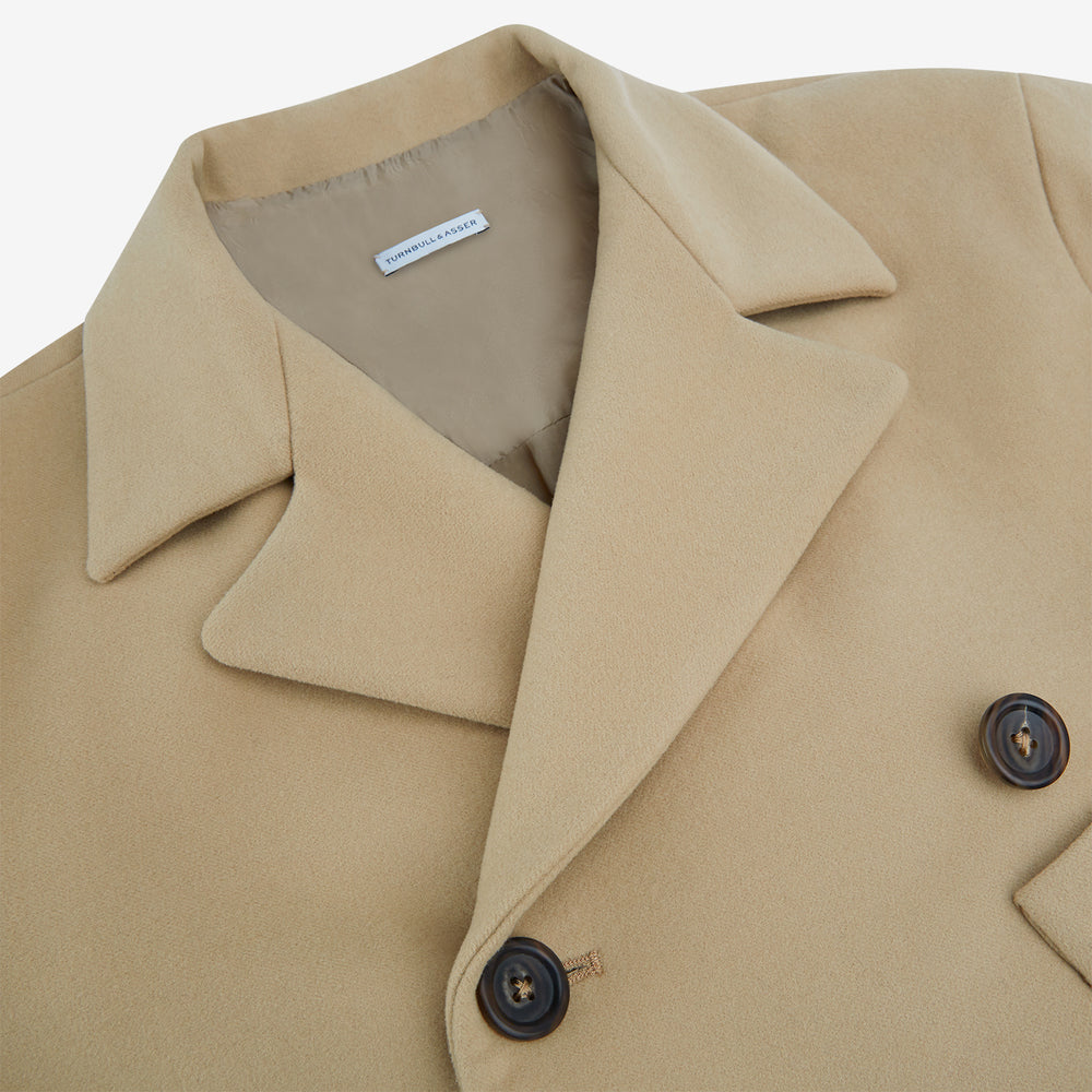 The Camel Wellington Double-Breasted Caban Coat by Turnbull & Asser features wide lapels, dark buttons, front flap and chest pockets, plus buttoned cuffs—perfect for elevating your formal wear collection.