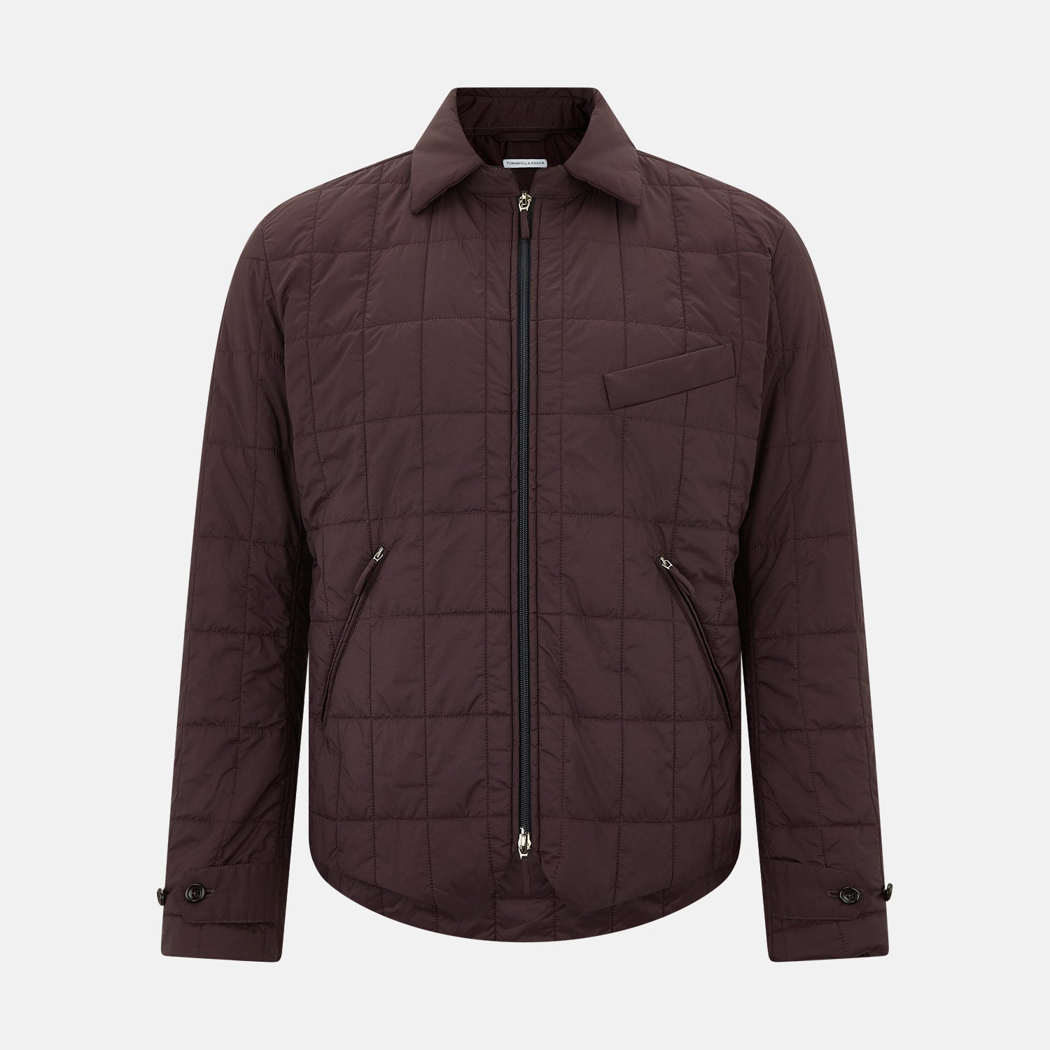 View 1 of product The Battersea Burgundy Quilted Jacket by Turnbull & Asser is a men's elegant outerwear featuring a front zipper, zippered side pockets, chest pocket, pointed collar, and buttoned cuffs, shown on a plain white background.