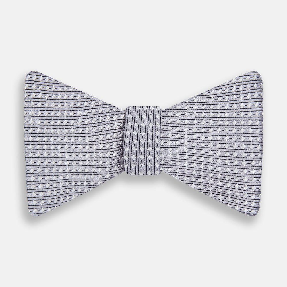 The Turnbull & Asser Silver and White Square Silk Bow Tie features a subtle geometric pattern, ideal for formalwear, and is displayed against a plain white background.