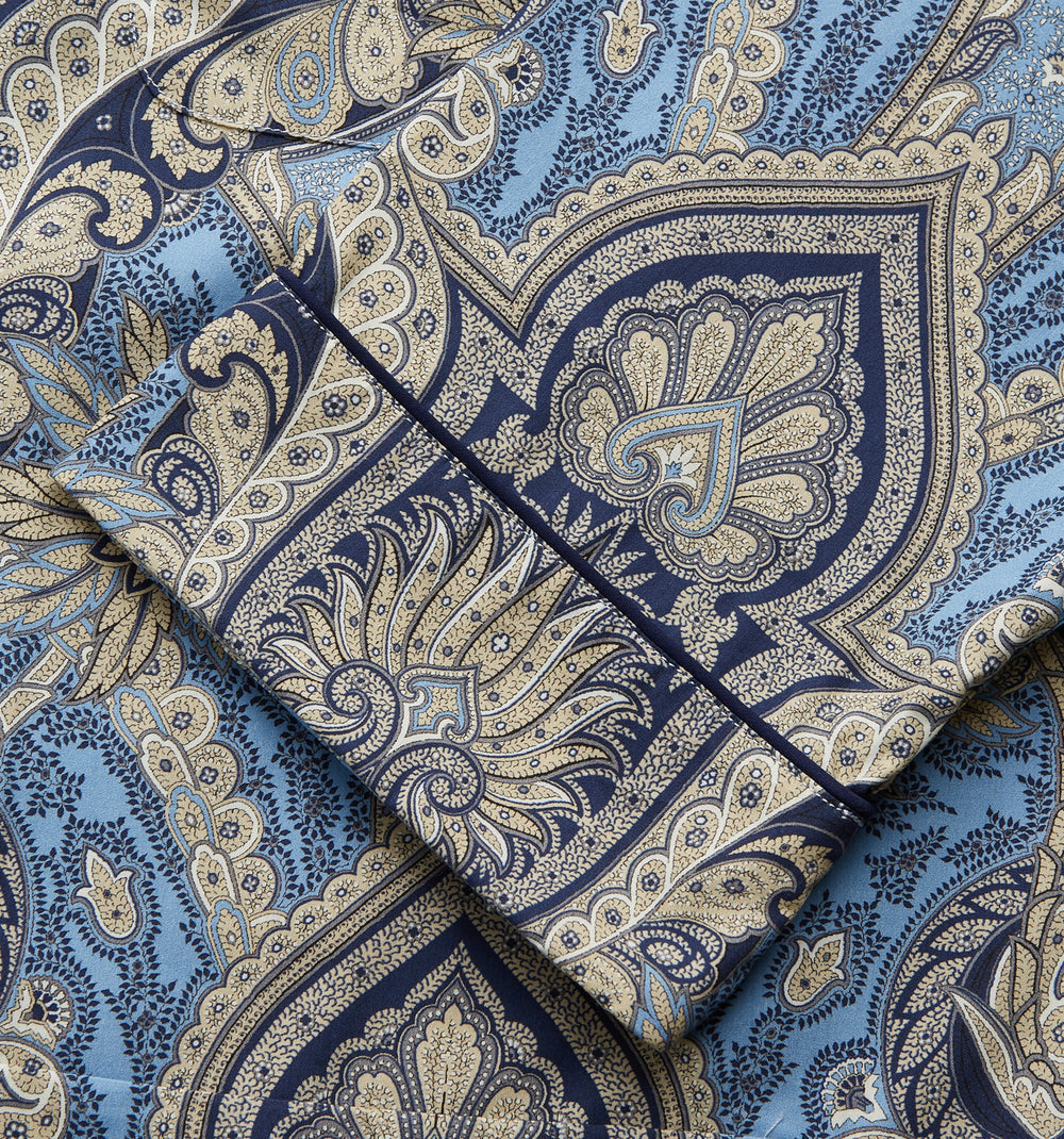 The Turnbull & Asser Pale Blue Baroque Silk-blend Hyde Pyjama Set features a long-sleeve button-up shirt and pants in a blue and beige paisley pattern, shown flat on a white background.