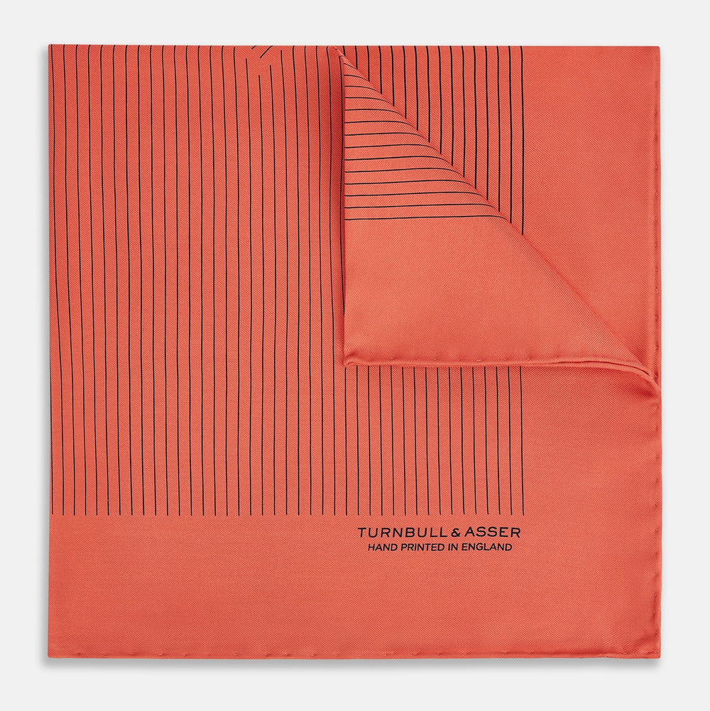 The Orange Stripe Silk Pocket Square by Turnbull & Asser features thin black vertical lines and "TURNBULL & ASSER HAND PRINTED IN ENGLAND" in the corner, neatly folded on a white background.